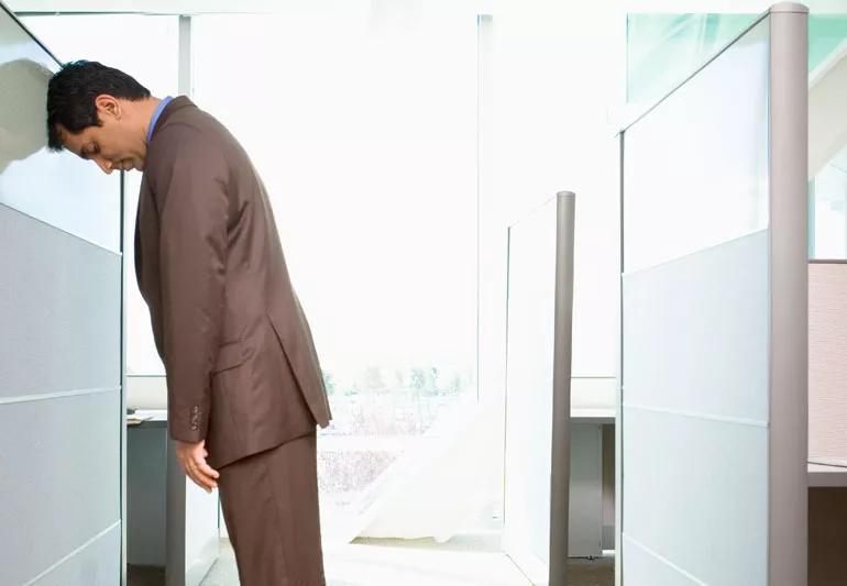 Man hitting head against cube wall in frustration