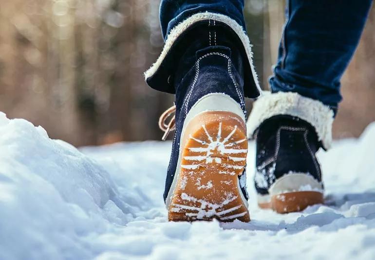 Person walking in winter boots on a path that has been shoveled or cleared.