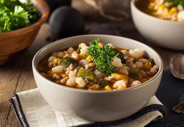 Hot homemade white bean chicken chili with parsley garnish in a white bowl sitting on a cotton napkin.