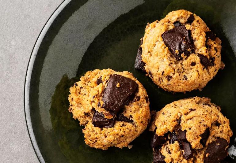 Chocolate chunk and nut chewies displayed on a dark green plate.