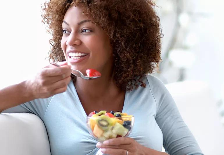 A woman eating a bowl of fruit.