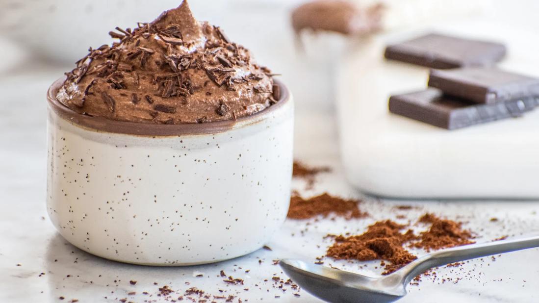 Chocolate espresso mousse in serving crock, with spoon, cocoa powder and chocolate nearby