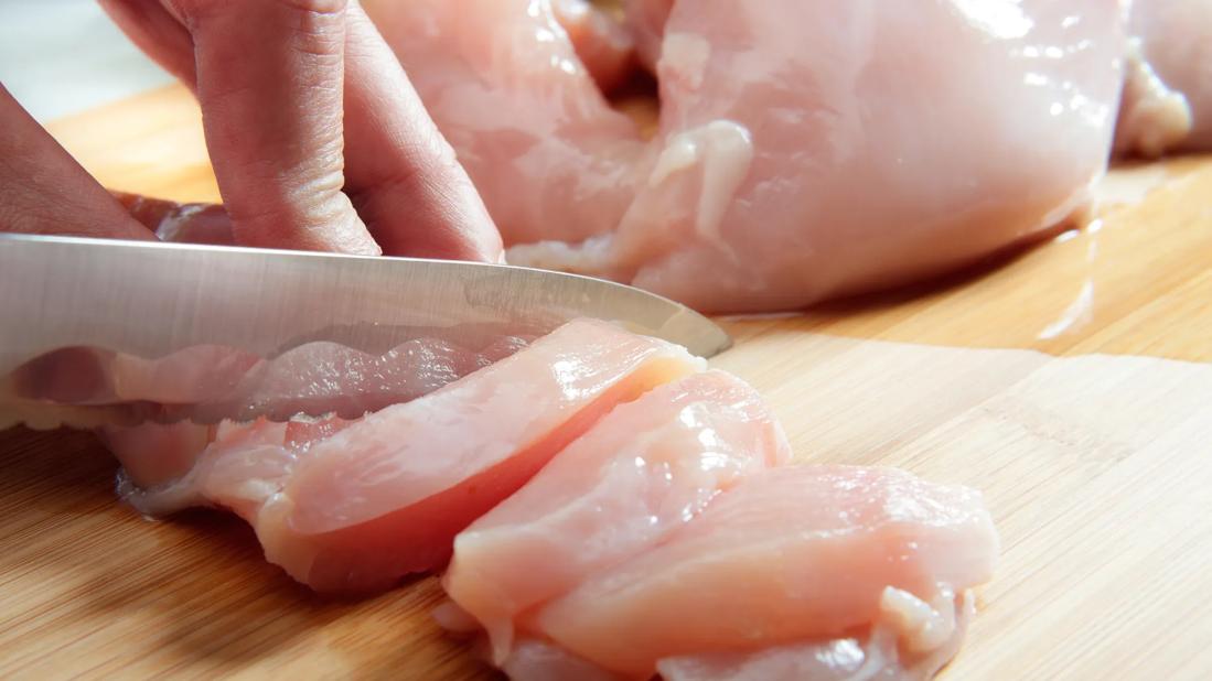 Raw chicken being cut up on cutting board