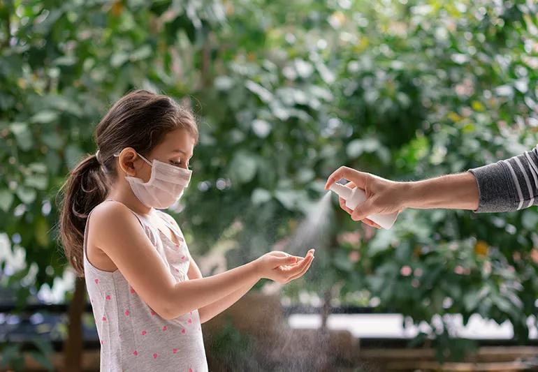 Father squirts antibacterial hand sanitizer in daughter's hands.