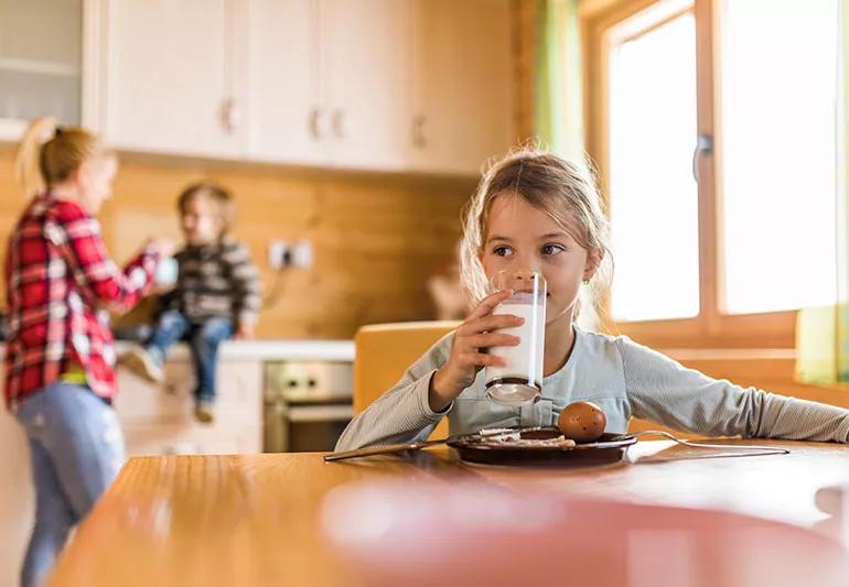 Child drinks milk while eating breakfast that includes a hardboiled egg