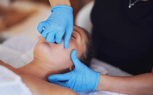 Massage therapist massaging patient's cheek and jaw area
