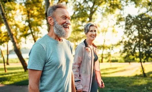 Older couple walking outside in a sunny park