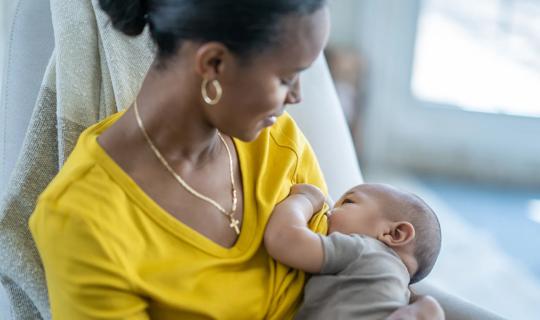 Mom in yellow shirt breastfeeding her baby