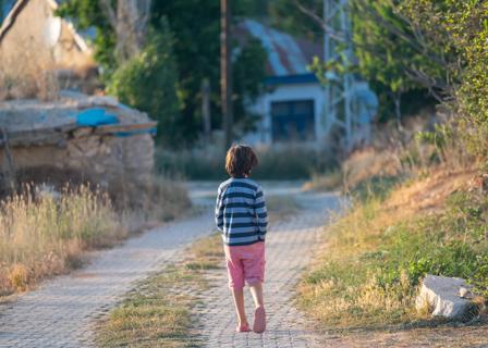 Young boy wandering alone down a roadway