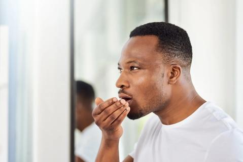 Person breathing into their hand to see if they have bad breath