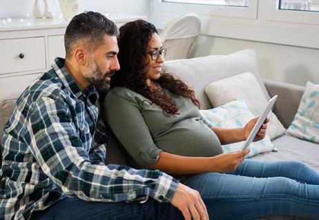 Pregnant woman sitting with husband on couch