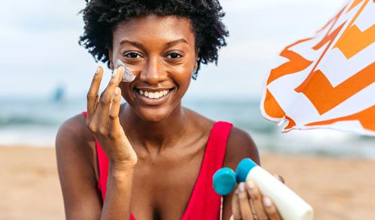 Person applying sunscreen to their face while at the beach