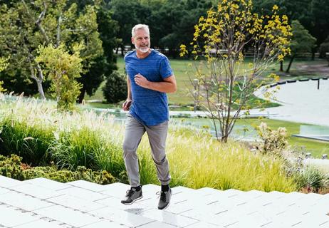 Older man jogs up steps at park during morning walk.