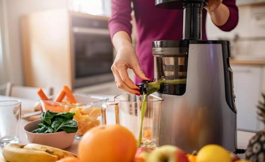 Juiced fruits and veggies dispensing from a juicer on counter in kitchen