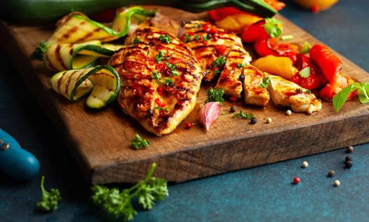 Grilled chicken with summer vegetables on cutting board