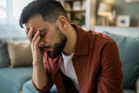 Person sitting with hand of face, eyes closed