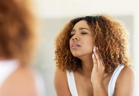 woman checking skin in mirror