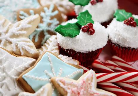 A plate of holiday desserts featuring cupcakes, frosted cookies and candy canes