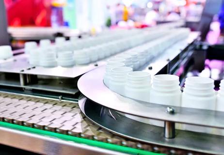 Closeup of the manufacturing process of filling pill bottles on the mechanized assembly line.