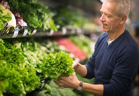 man shopping for greens at store