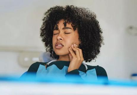 Person in dentist chair with tooth pain, clutching cheek