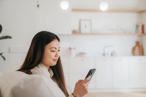 Smiling person looking at their phone, sitting on couch