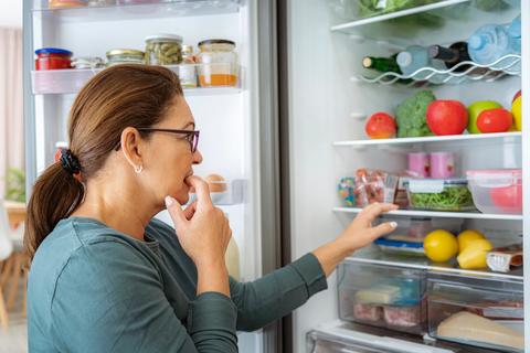 Person standing at open refrigerator, trying to decide what they want