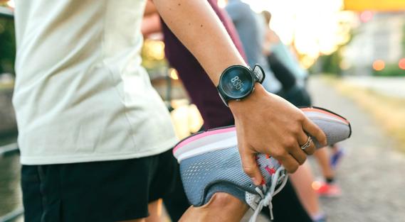 Person stretching leg in prep for a run, wearing a smartwatch on wrist