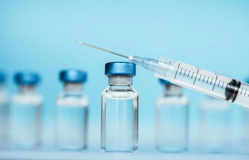 Glass vial of medicine with syringe balanced against it