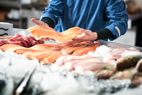 Fish market worker selecting a cut of fresh fish