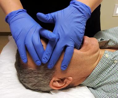 Osteopathic practitioner manipulating patient's face
