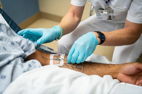 A nurse places an IV line in a patient's arm.