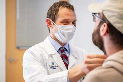 Seth Rotz, MD, exams patient's throat during clinical exam