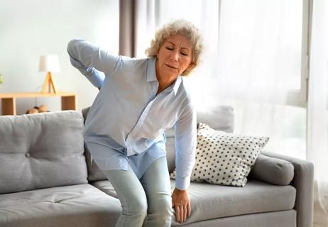 woman getting up from couch with back pain