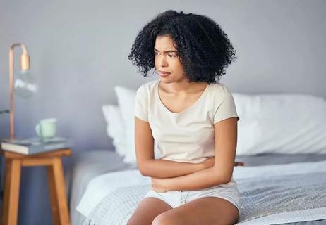 woman sitting on bed, cradling her stomach