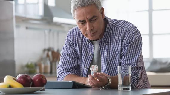 Man examining prescription bottle in kitchen
