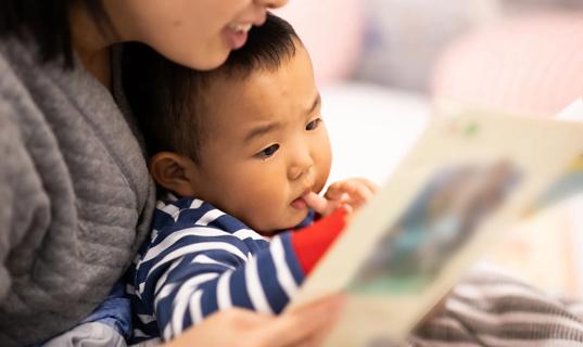 Caregiver holding baby, reading them a book
