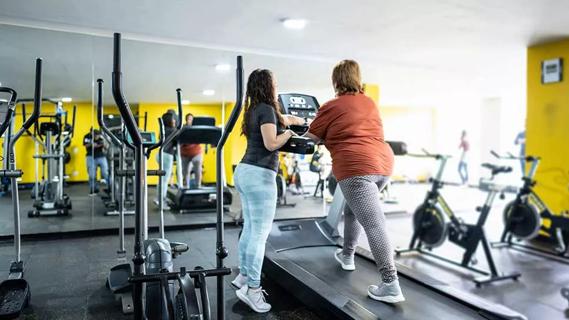 personal trainer working with person on treadmill at gym