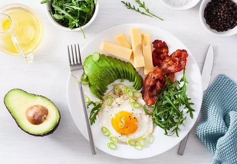 Eggs, avocado, bacon and cheese on a plate.