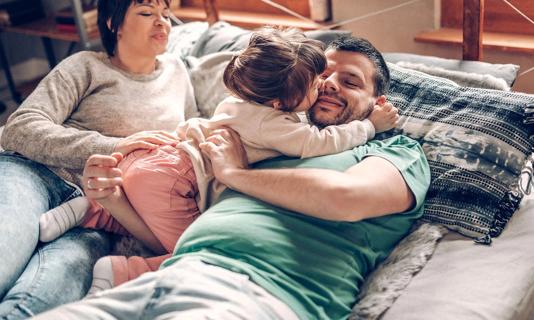 Partners lying on bed playing with their toddler