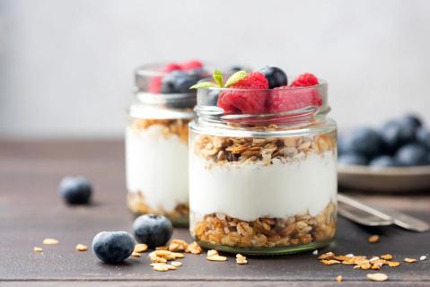 Two glass jars filled with layers of Greek yogurt, oats and fruit