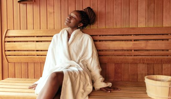 Smiling person in a robe sitting in a sauna