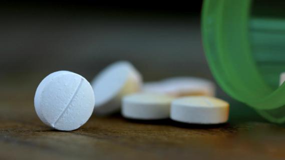 Pills scattered on table near bottle