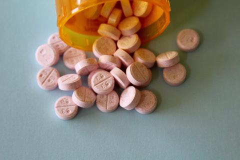 Bottle of medication on its side, with pills lying scattered on the table