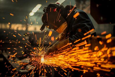 Factory worker cutting metal