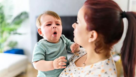 Caregiver holding crying, coughing baby