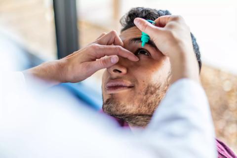 Adult receiving eye drops from a healthcare provider
