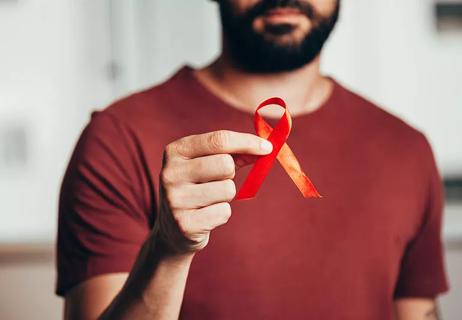 Person holding a red ribbon for HIV/AIDS awareness