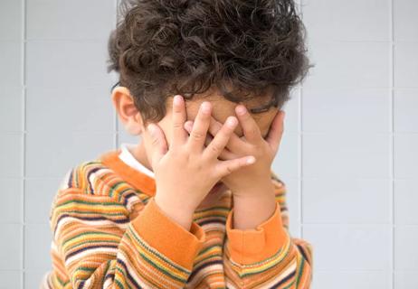 small boy covers eyes in bathroom