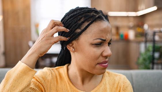Person grimacing, scratching their head
